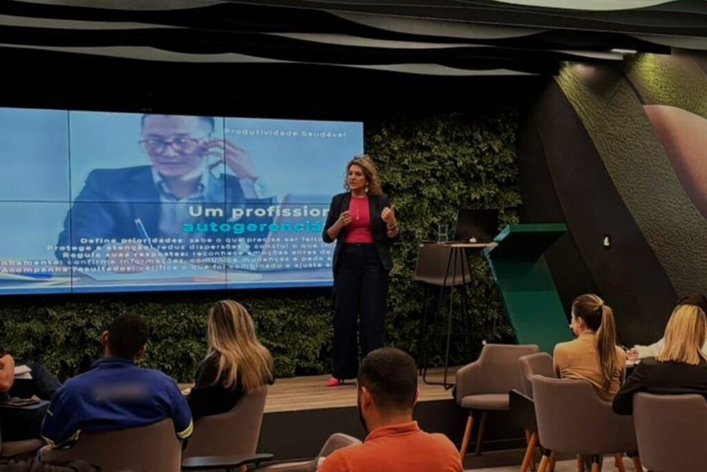 Mariana Marco no palco, durante uma palestra para uma empresa.