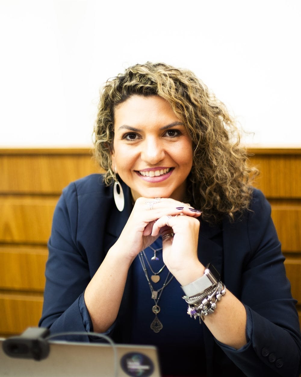 Mariana Marco sorrindo, sentada com as mãos apoiadas no queixo.