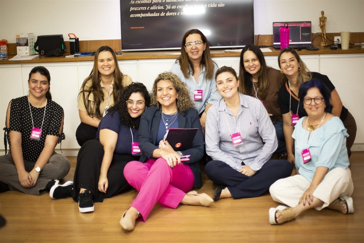 Mariana Marco sentada no chão com uma turma de orientadoras profissionais.